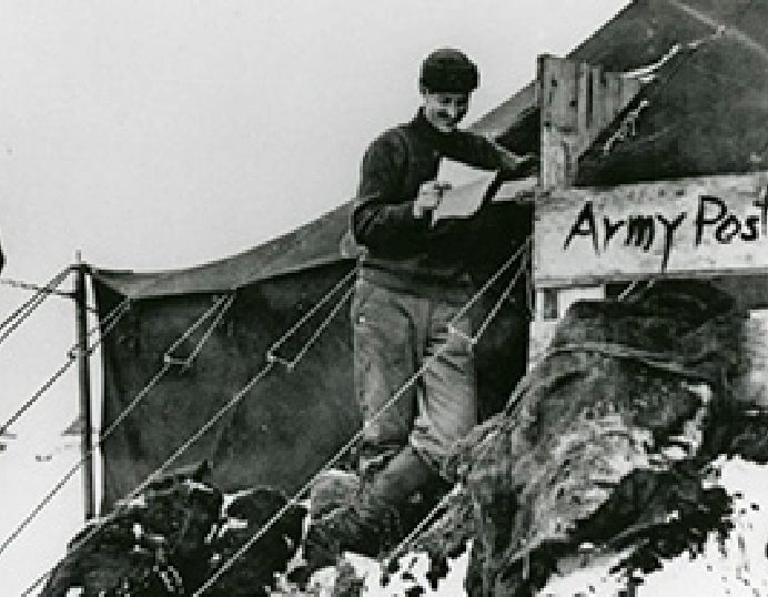 Soldier reading mail at a snowy Army Post tent