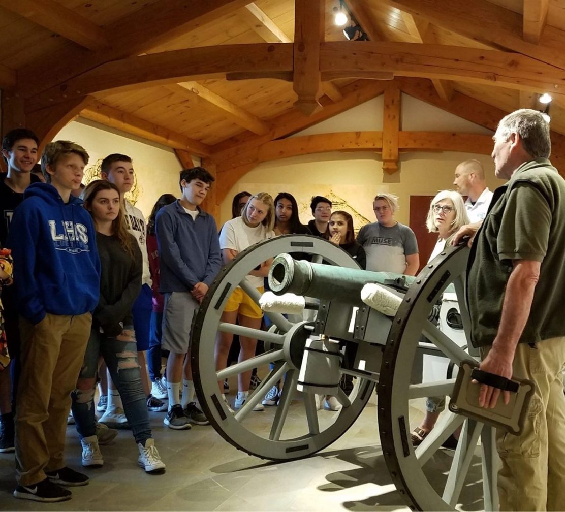 Students on a guided school tour viewing a cannon with a docent