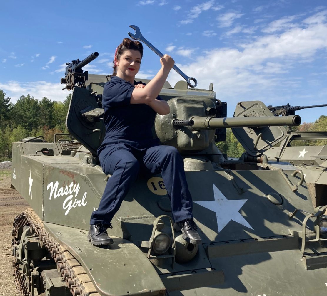 Costumed presenter posing with a wrench on a WWII tank