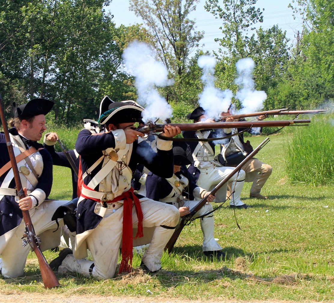 Revolutionary War re-enactors firing muskets at a living history event