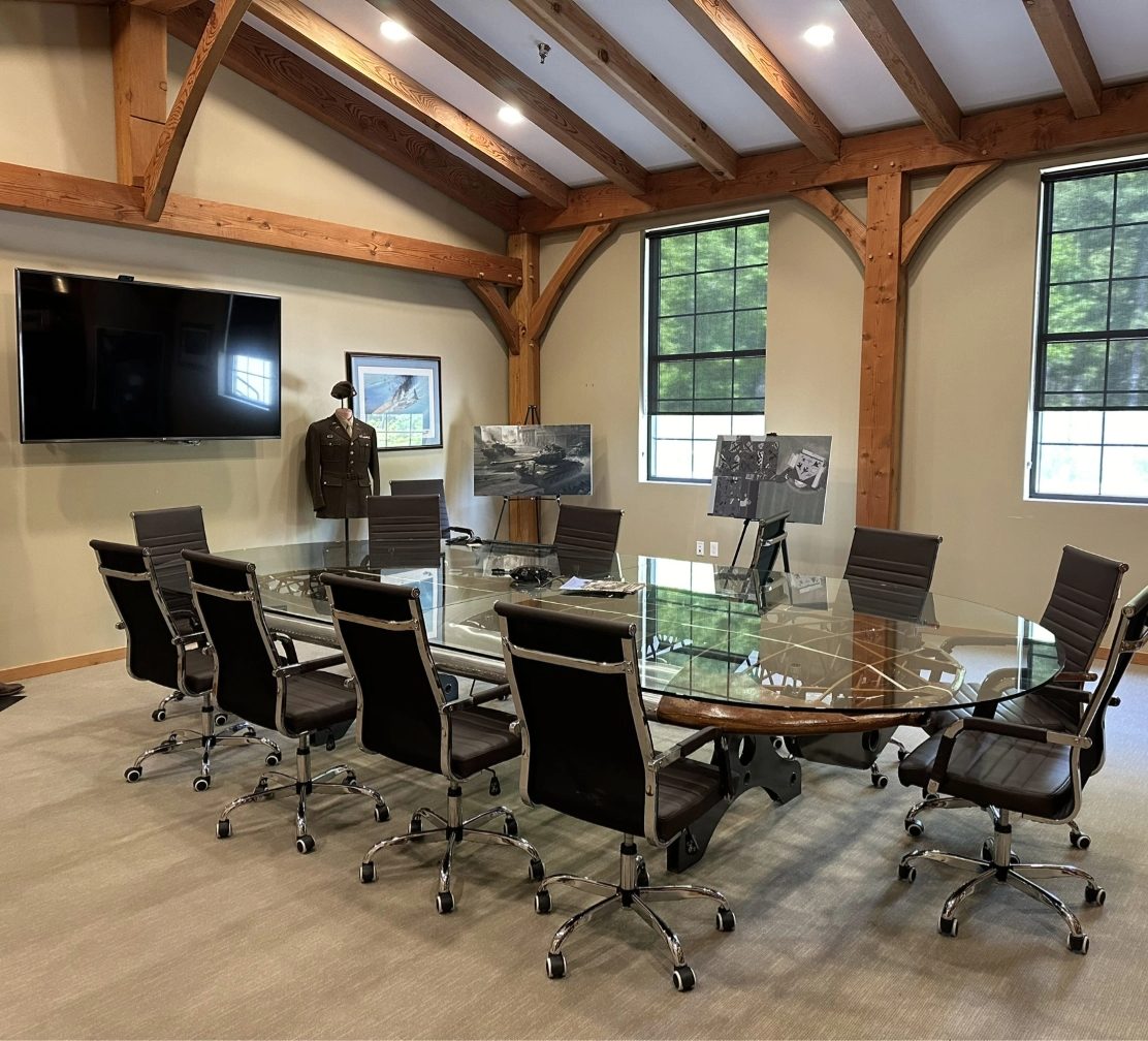 Post-and-beam conference room with a glass-top table made from a WWII biplane wing