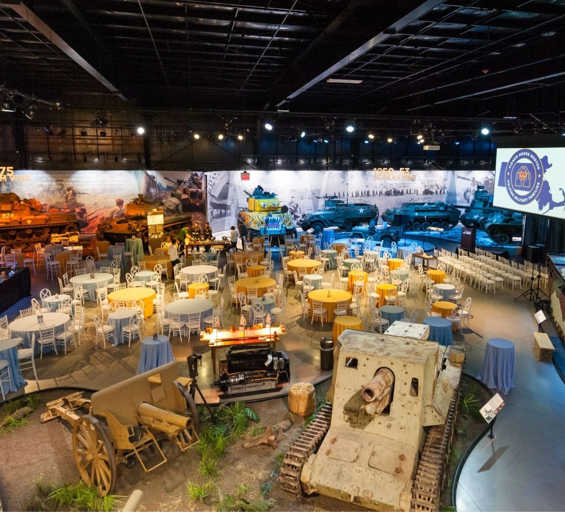 Banquet tables arranged among tanks and aircraft in the museum main gallery
