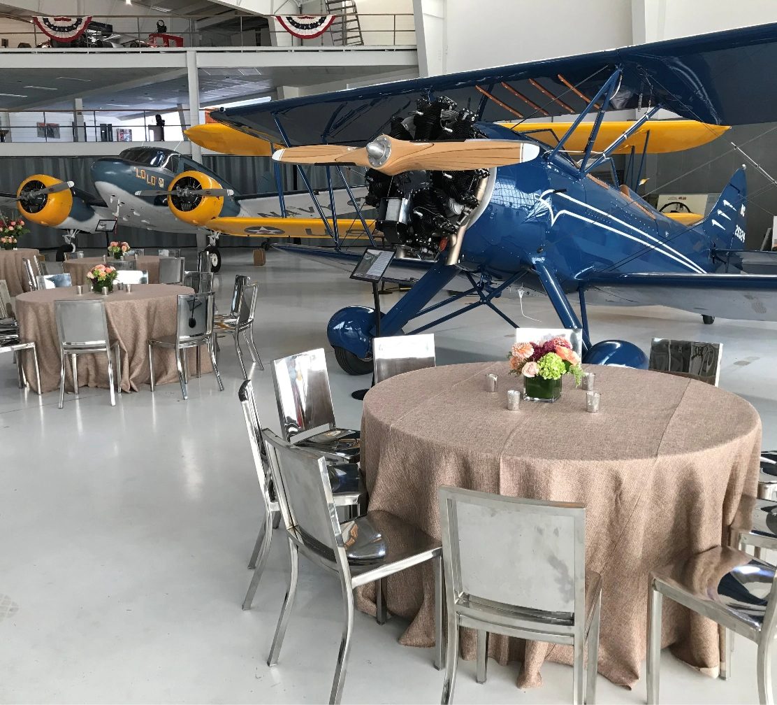 Vintage biplanes and round dining tables inside the seasonal aircraft hangar