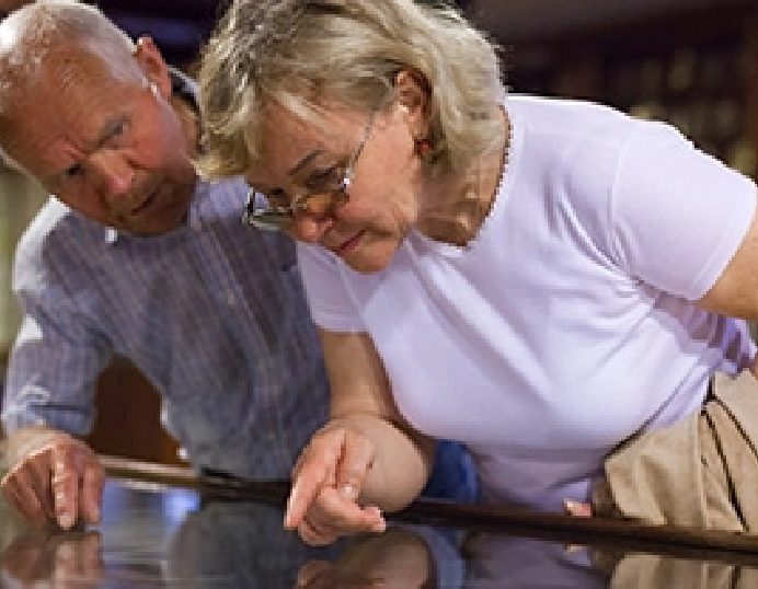 Older couple closely examining a museum artifact in a glass display case
