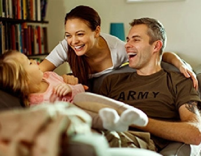 Military family relaxing at home, a soldier in an Army shirt with his wife and young daughter