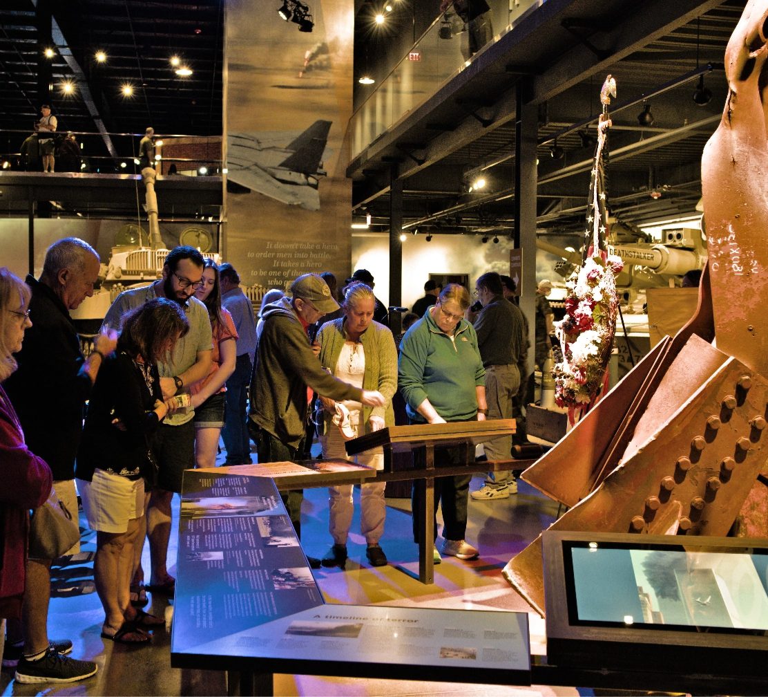 Museum visitors examining an artifact display in the exhibit hall