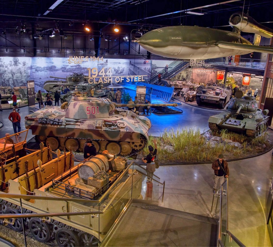 Wide view of the museum exhibit hall with historic tanks beneath the 1944 Clash of Steel mural